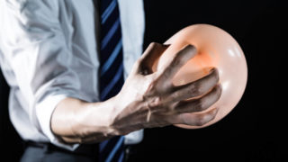 風船を握りつぶそうとしてる男性